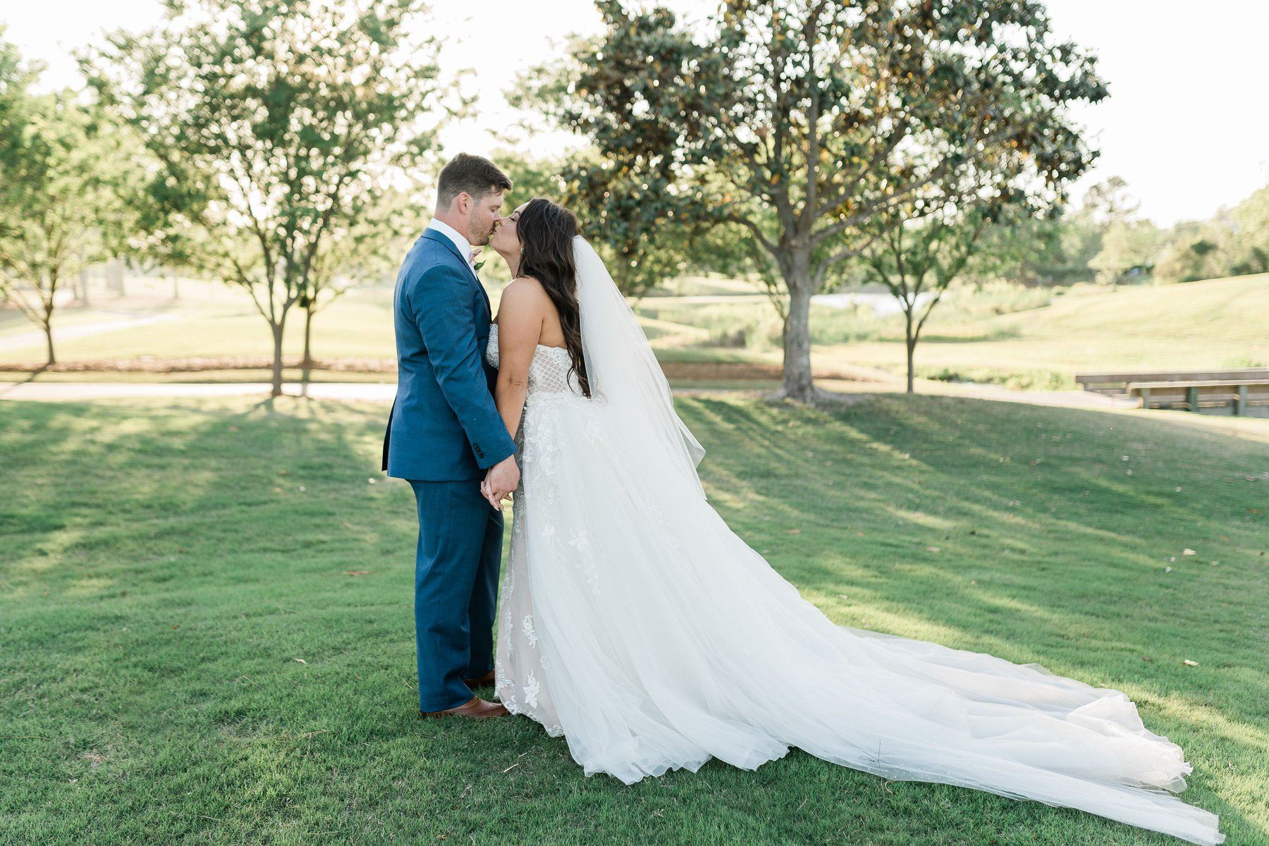 Сouple wearing a white gown and a blue suit on the grass