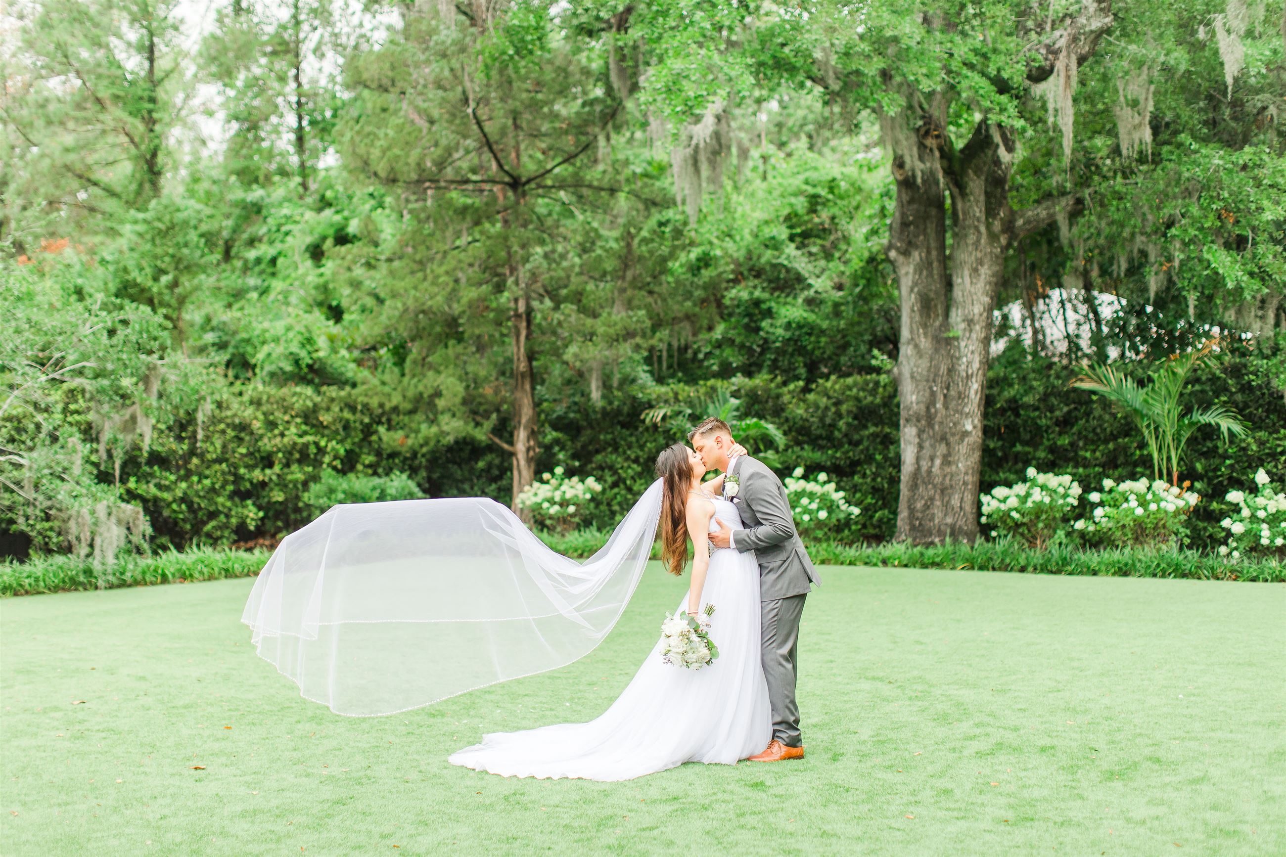 Сouple wearing a white gown and a gray suit on the grass