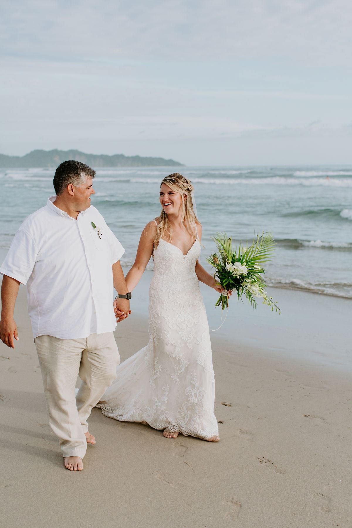 Сouple wearing a white gown and a white suit on the beach